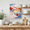 wall art canvas painting in the kitchen depicts a cozy scene with latte art coffee, strawberries, croissants and an open book.