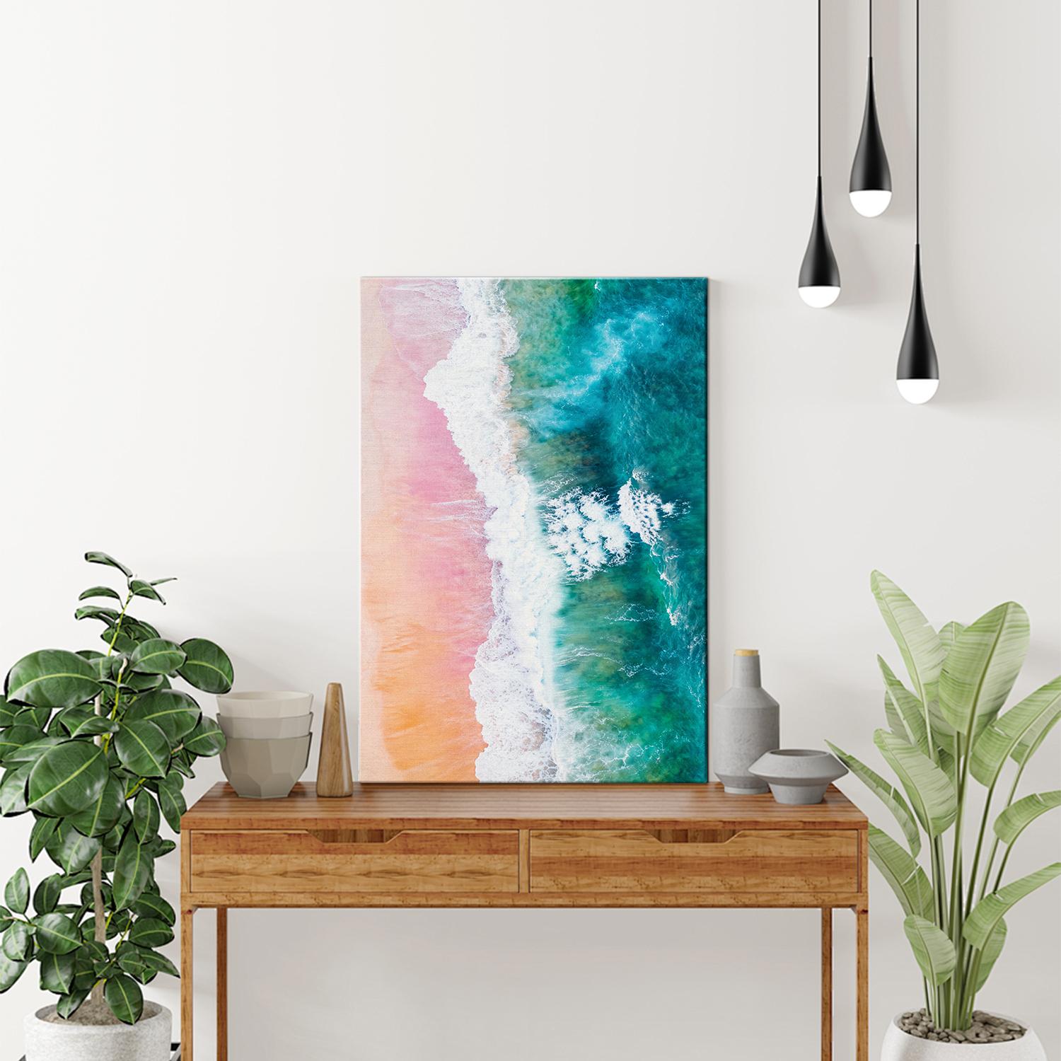 wall art canvas on the table depicts pink sand beach and white waves