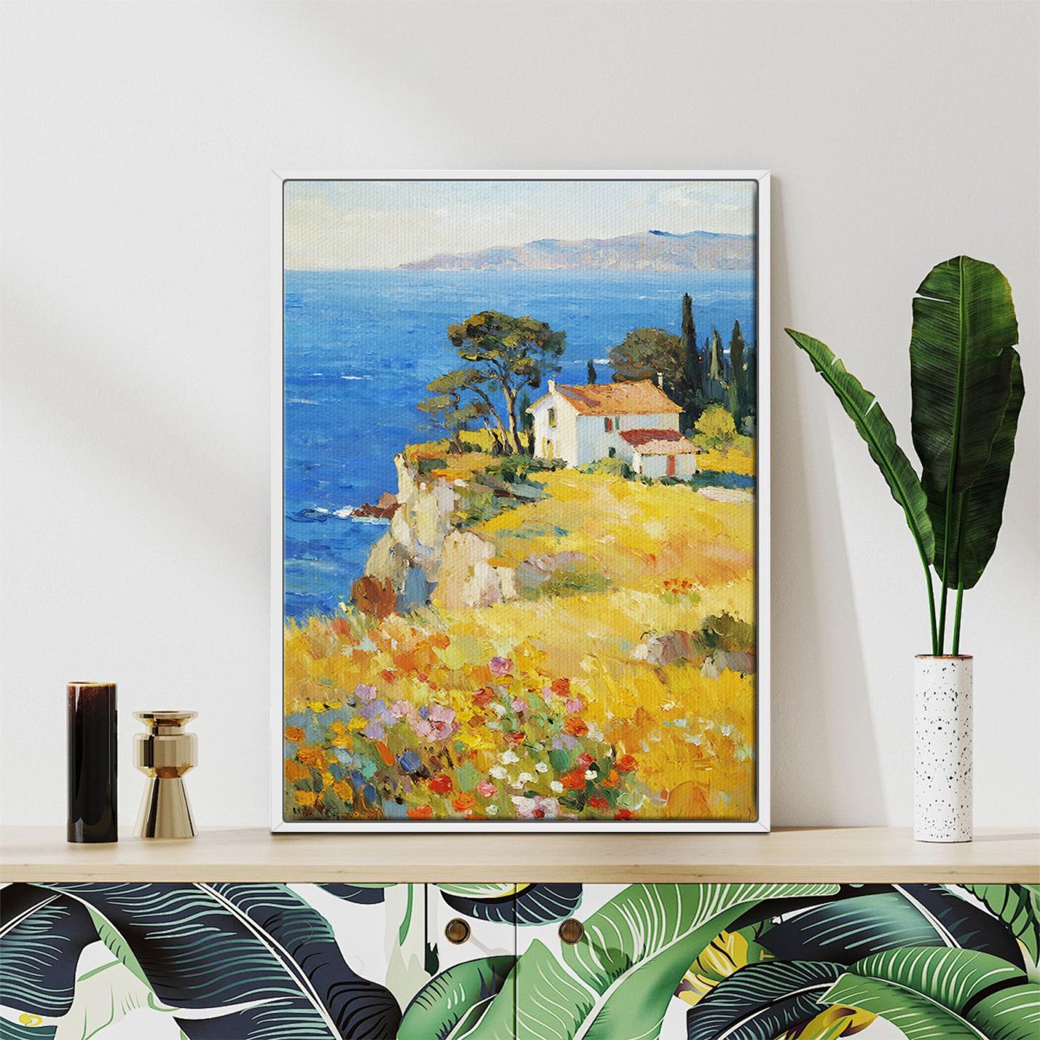 white frame wall art painting depicting a cliffside cottage by the sea
